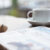 white coffee cup on table with business journal in front of it